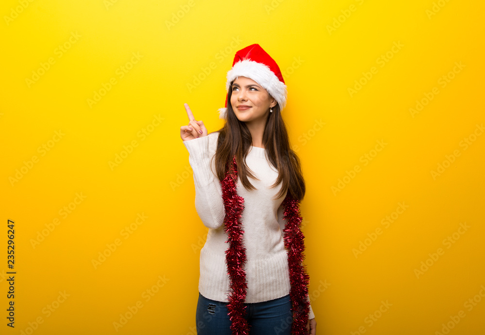 Teenager girl celebrating christmas holidays pointing with the index finger a great idea Teenager girl celebrating christmas holidays pointing with the index finger a great idea