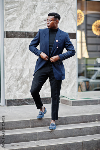 Amazingly looking african american man wear at blue blazer with brooch, black turtleneck and glasses posed at street. Fashionable black guy.