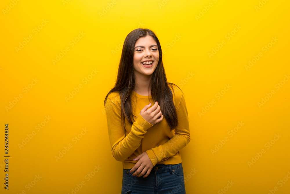 Obraz premium Teenager girl on vibrant yellow background smiling a lot while putting hands on chest