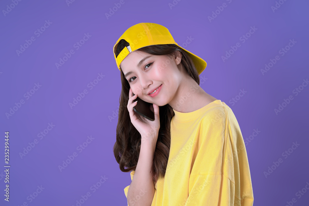 Chinese woman use smartphone to call her friend yellow t-shirt clothing, purple background Chinese woman use smartphone to call her friend yellow t-shirt clothing, purple background