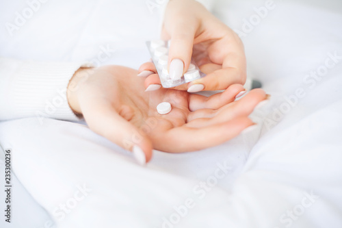 Cold and flu. Woman hold pills in hand  lying on the bed
