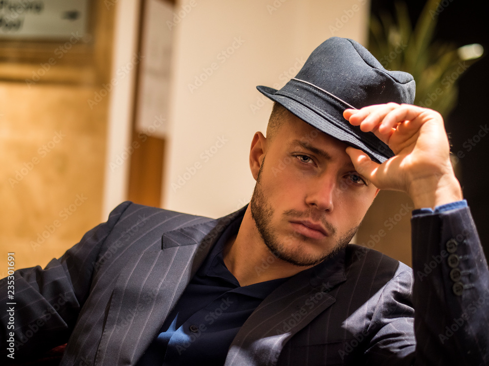 Handsome elegant man in hotel or night club lounge, wearing business suit  and fedora hat, looking at camera Stock Photo | Adobe Stock