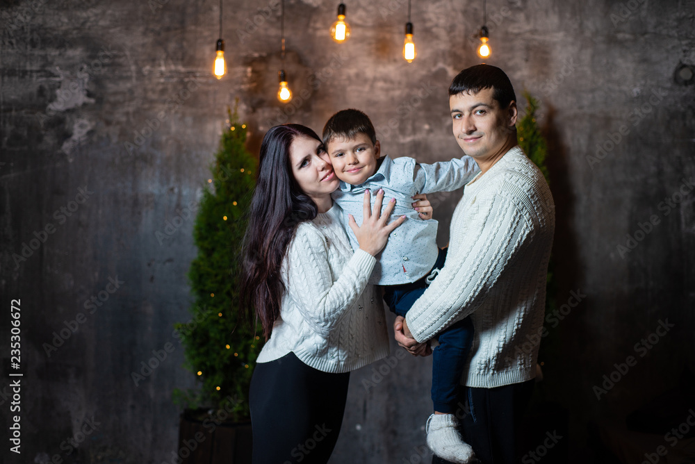 New year's portrait of a happy family near Christmas trees and walls