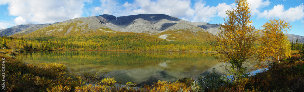 Panorama. Mountain lake surrounded by autumn forest in the background of the Khibiny Mountains