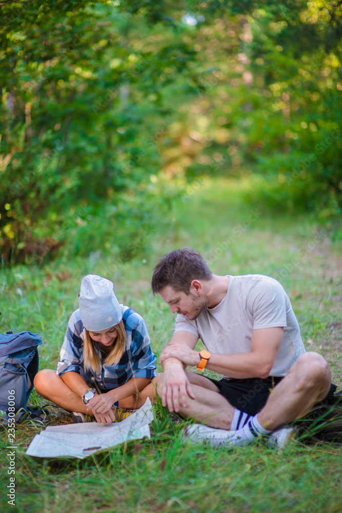 Young couple resting and checking the map inside the forest. Hiking concept in the mountain in summer Young couple resting and checking the map inside the forest. Hiking concept in the mountain in summer
