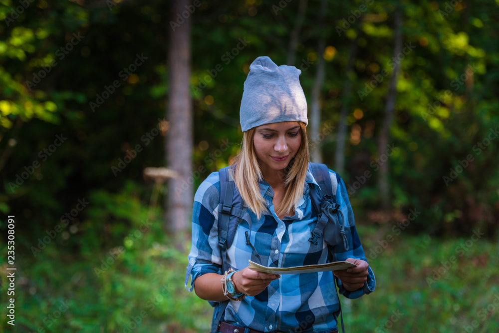 Young woman walking alone in the woods holding a map. Hiking concept in the mountain in summer Young woman walking alone in the woods holding a map. Hiking concept in the mountain in summer
