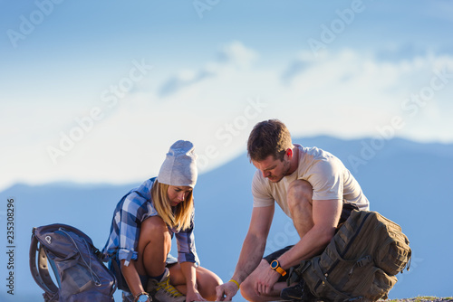 A couple checking their position on the map and enjoying the peak of the mountain, cliff at sunset.