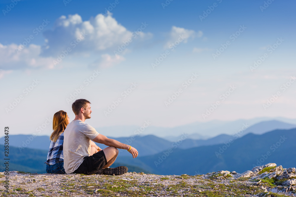 A couple enjoying the view on a peak of the mountain, cliff at sunset. Success, winners.