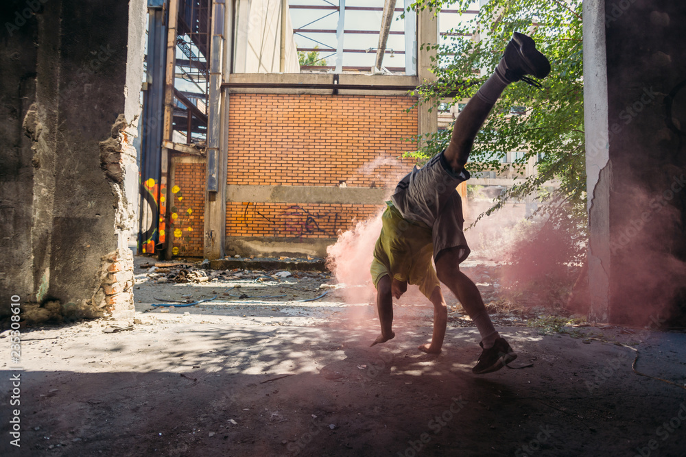 Young man doing parkour handstand around colored smoke bomb Young man doing parkour handstand around colored smoke bomb