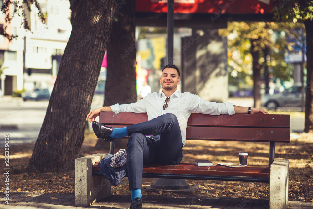 Fototapeta premium Young businessman is outdoors, relaxing and enjoying in the park
