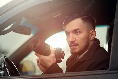 Close-up - Young Man Photorapher Sitting In The Car And Quickly Took A Photo On A Digital Camera. Concept Of Espionage And Photography photo