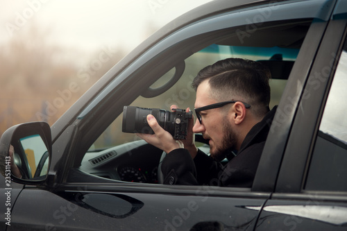 Young Male Photographer Takes A Camera With A Zoom Lens And Takes Pictures. Concept Of Espionage And Photography