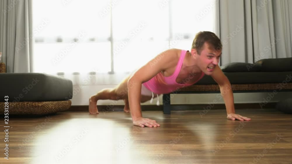 Playful handsome guy in a pink t-shirt engaged in fitness, in the living room of his house. Playful handsome guy in a pink t-shirt engaged in fitness, in the living room of his house.
