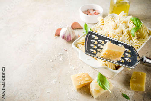 Italian food, fusilli pasta with grated parmesan cheese and basil, light stone table copy space top view photo