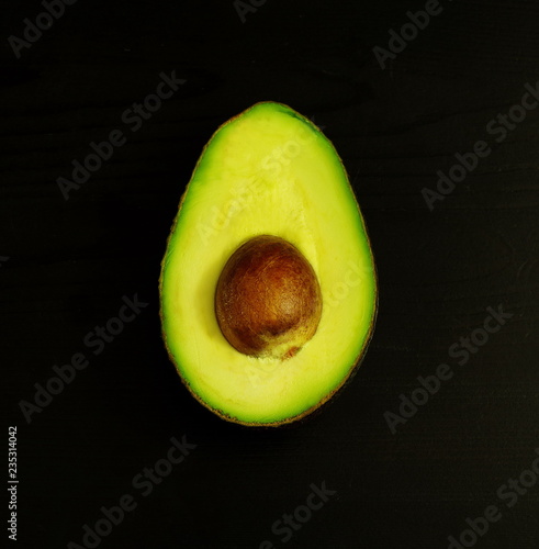 Half of avocado on black background, healthy lifestyle, diet concept