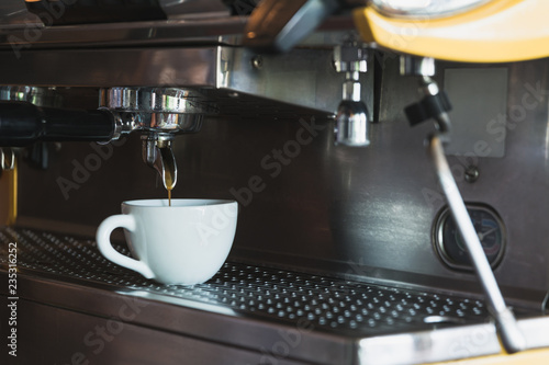 A coffee cup with coffee machine in coffee shop.