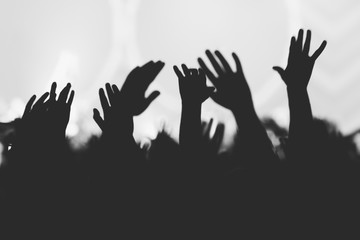 Hands silhouettes of the crowd raised up at music show. Black and white picture