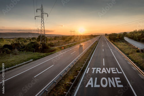 Beautiful Countryside Motorway with a Single Car at sunset with motivational message I Travel Alone