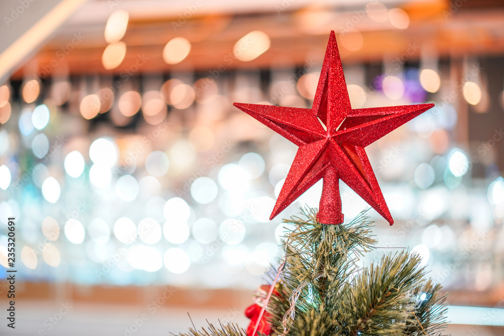 Red star decoration on the three with blur big Christmas tree behide. Red star decoration on the three with blur big Christmas tree behide.