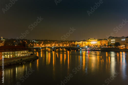 Illuminated classical buildings and street lights reflecting on the Vltava river in Prague in a cold winter night - 1 © gdefilip