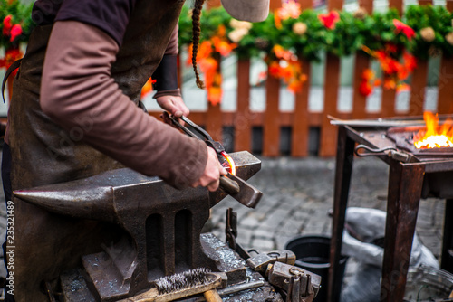 A blacksmith hammering a red hot horse nail at s Czech Christmas market in Prague - 4