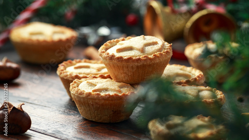 Foto British Christmas mince pies with decoration, gifts, green tree branch on wooden