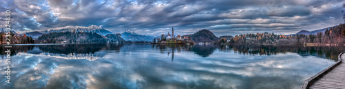 Panoramic shot of the Lake Bled in Slovenia during twilight with the reflection of the surrounding hills and mountains