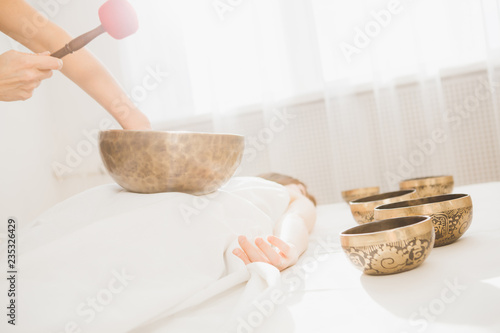 Girl doing massage therapy singing bowls in the Spa