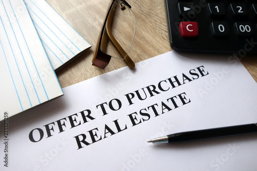 Offer to purchase real estate with pen, calculator and   glasses on desk