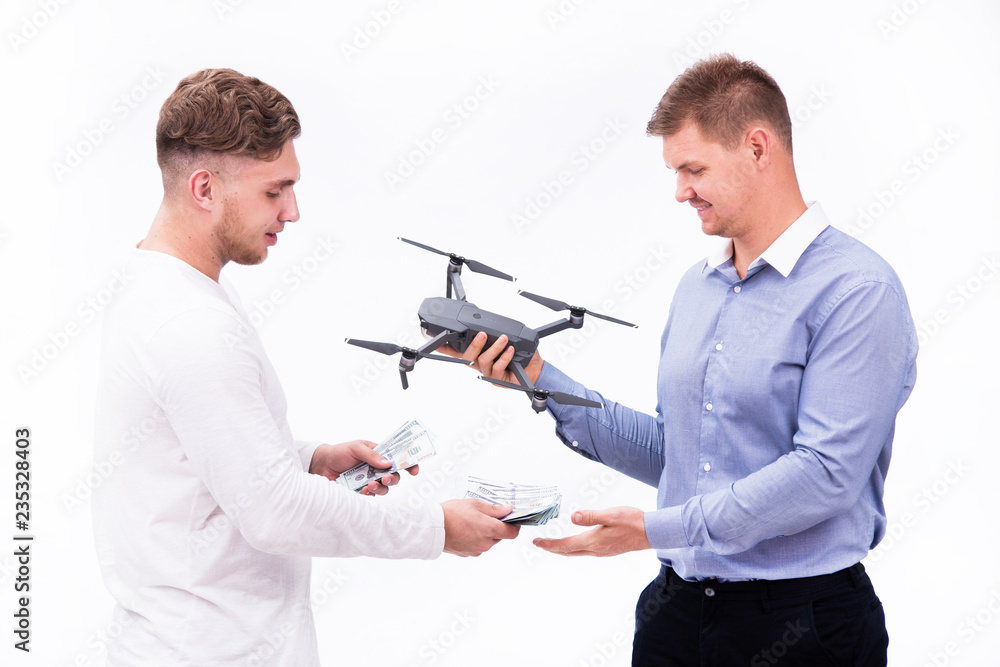 One guy holds money in his hands, the other holds an aerial drone. Theme buying and selling drones One guy holds money in his hands, the other holds an aerial drone. Theme buying and selling drones