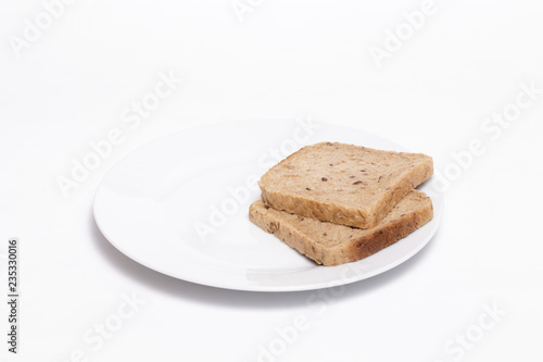 Full grain bread slices on a white dish against white background