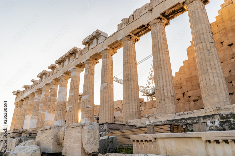 Close up of the beautiful ionic columns of the ancient Parthenon Temple, in the Acropolis in Athens, Greece, in the morning, with golden sunlight.