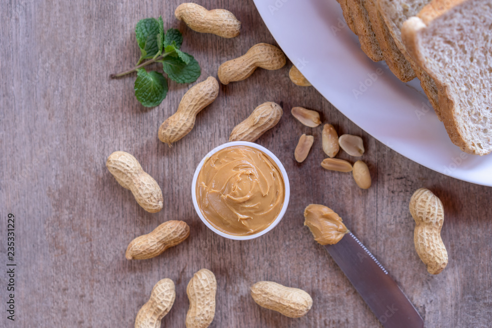 Fototapeta premium Creamy peanut butter with nut and bread on wood table.
