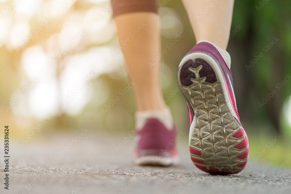 Naklejka premium Close up woman shoe running on the road, jogging alone at park, Sports healthy lifestyle concept.