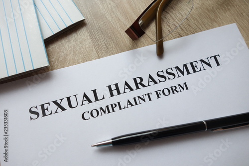 Sexual harassment complaint form with pen, calculator   and glasses on desk