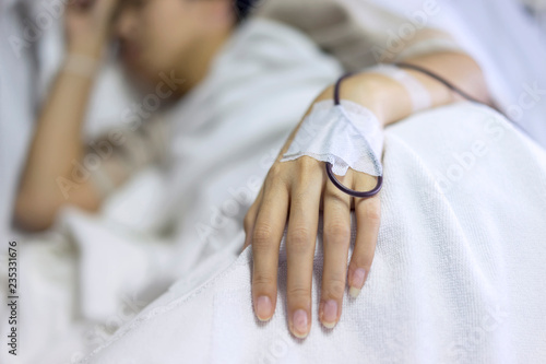 Close up, woman add blood in hand and blurry of patient illness sleeping on hospital bed. Medical equipment concept.