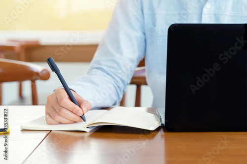 Businessman planning writing note and working with laptop computer on desk. Writing something idea on notebook or check list, Learning concept..