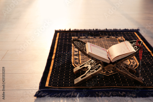 Photography Rehal with open Quran and Muslim prayer beads on rug indoors