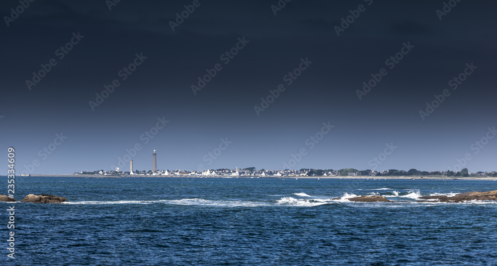 Landscape with rocky coast and lighthouse on a windy day in Guilvinec, Brittany, France