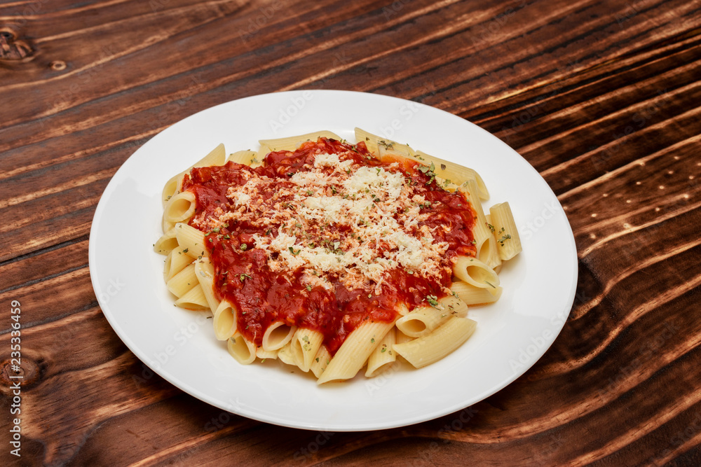 close in penne meal with red sauce and grated cheese, wooden background close in penne meal with red sauce and grated cheese, wooden background
