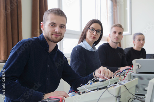 Group of young students in technical vocational training with teacher, the lesson in technical college, with young male student in front of camera.