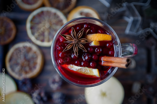 Homemade mulled wine with oranges, apples, cinnamon, cranberries and fir tree on rustic wooden background