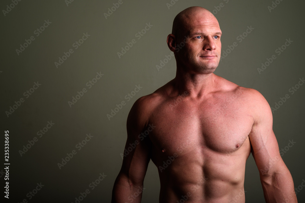 Fototapeta premium Bald muscular man shirtless against colored background