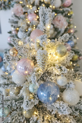 elegant beautiful new year and Cristmas tree with white, pink and blue toys under the instant snow 