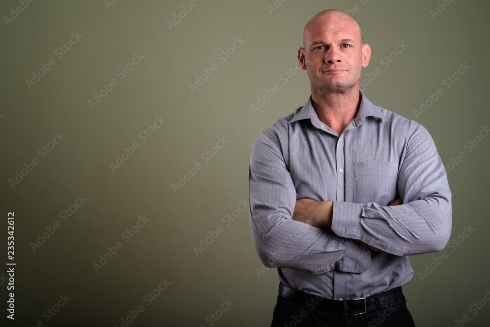 Fototapeta premium Portrait of bald muscular businessman against colored background