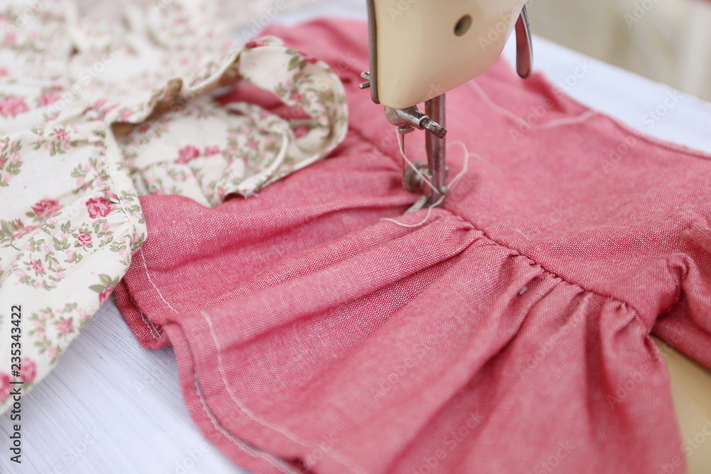 Φωτογραφία old vintage beige sewing machine and red little dress for girl and doll in ateli