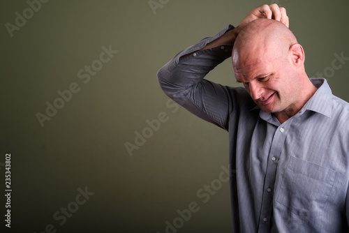 Portrait of bald muscular businessman against colored background