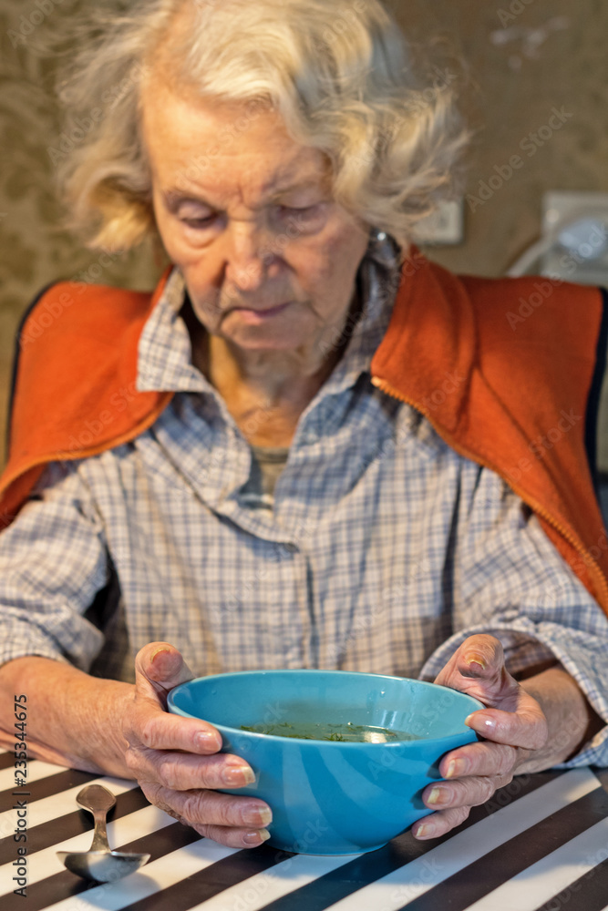 elderly woman holding a bowl of soup. health care and elderly people with poor health. elderly woman holding a bowl of soup. health care and elderly people with poor health.
