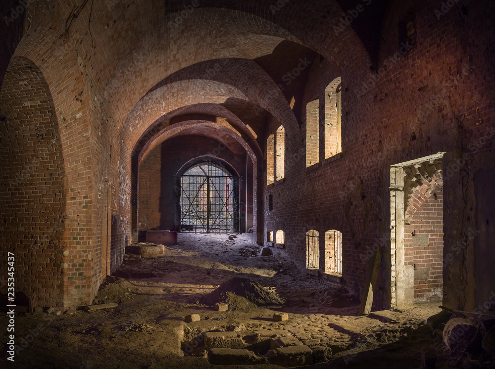 abandoned underground brick corridor with windows illuminated by counter light.