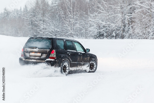extreme driving, the car is moving rapidly over the smooth snow and creates a spray of snow.